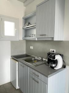 a kitchen with white cabinets and a sink at MAGGANARI MOMENTS 2 in Manganari