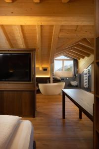 Schlafzimmer mit einem großen TV und einer Badewanne in der Unterkunft Camino Rustic Chic Hotel in Livigno