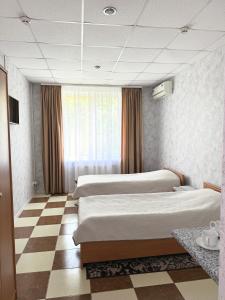 a bedroom with two beds and a checkered floor at Hotel Vesta in Brovary