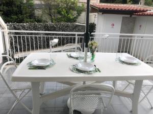 un tavolo bianco con piatti e bicchieri su un balcone di La Pomelia di Giò a Mondello