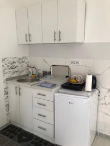 uma pequena cozinha com um lavatório e armários brancos em Apartman DB em Višegrad