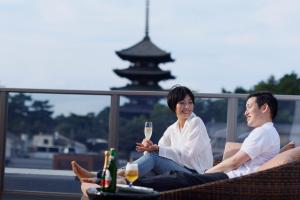 un hombre y una mujer sentados en un balcón con copas de vino en Ryokan Asukasou at the entrancne of Nara park, en Nara