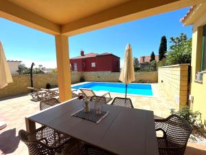 a patio with a table and chairs and a pool at Holiday home Summer escape 2 on Island Rab in Barbat na Rabu