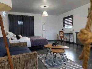 ein Schlafzimmer mit einem Bett, einem Tisch und einem Sofa in der Unterkunft "Koko Lodge" Lodge paisible avec terrasse, jardin et piscine in Rémiré