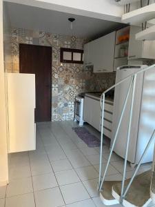 eine Küche mit weißen Geräten und Fliesenboden in der Unterkunft Casa na Barra de São Miguel in Barra de São Miguel