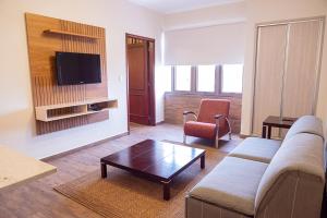 ein Wohnzimmer mit einem Sofa, einem Stuhl und einem TV in der Unterkunft Sabe Center in Asunción