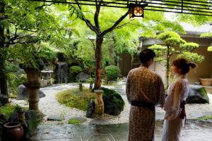 un hombre y una mujer de pie en un jardín en Ryokan Asukasou at the entrancne of Nara park, en Nara