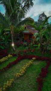 a house with a palm tree and a garden at Wina Wani Bungalows Tetebatu in Tetebatu