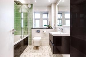 a bathroom with a toilet and a sink and a shower at Comfortable Home in Wandsworth by UndertheDoormat in London