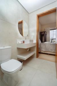 a bathroom with a toilet and a sink and a bed at Pousada Canto da Montanha in São Thomé das Letras