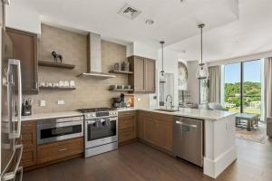 a large kitchen with wooden cabinets and stainless steel appliances at 'The Views Over Pack Square Park' A Luxury Downtown Condo with Mountain and City Views at Arras Vacation Rentals in Asheville