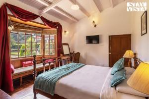 a bedroom with a bed and a window at StayVista at Greenwood Bungalow - Indoor & Outdoor Game in Ooty