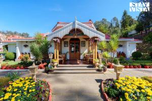 a house with a porch and flowers in front of it at StayVista at Greenwood Bungalow - Indoor & Outdoor Game in Ooty