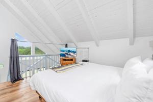 a white bedroom with a bed and a television at Tidal House 2 in Ocean Shores