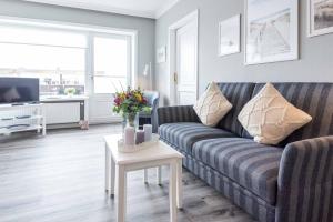a living room with a couch and a table with flowers at Syltdomizil Morgensonne in Wenningstedt