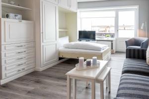 a white bedroom with a bed and a desk at Syltdomizil Morgensonne in Wenningstedt