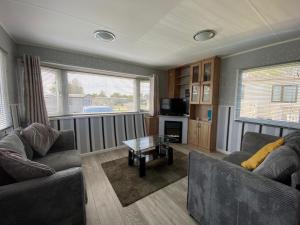 Sala de estar con 2 sofás y mesa en Homely Caravan Just A Short Walk To Hembsy Beach In Norfolk Ref 00036ba, en Hemsby