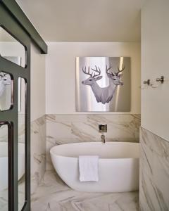 baño con bañera y una foto de un ciervo en The Crawford Hotel en Denver