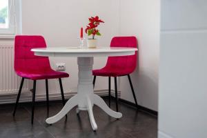 a table with two red chairs and a white table with a plant at City Center Sanctuary in Braşov