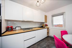 a kitchen with white cabinets and a table and pink chairs at City Center Sanctuary in Braşov