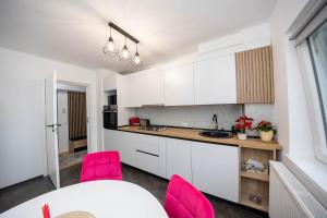 a kitchen with white cabinets and pink chairs at City Center Sanctuary in Braşov