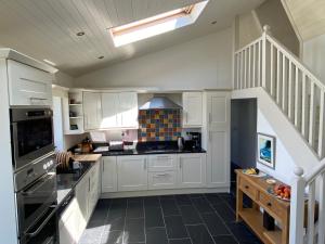 a large kitchen with white cabinets and a staircase at House Gowlane in Castlegregory