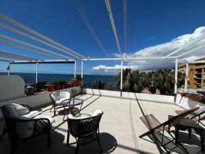 Un balcón con sillas y mesas y vista al mar. en Apartment La Luna- First Line Beach, en Benalmádena