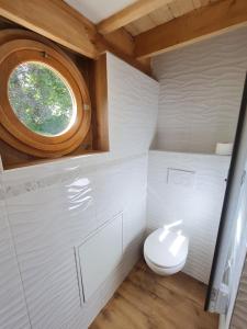 uma casa de banho com um WC e uma janela redonda em Cabanes du Domaine des Fées em Dole