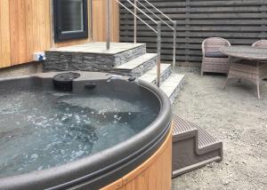 a hot tub in a yard with a table and a patio at Blenkett Wood Lodge Park in Grange
