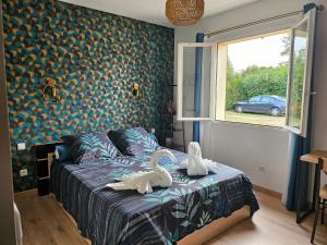 two swans on a bed in a bedroom with a window at Les chambres d'Estelle in Guécélard