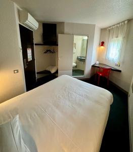um quarto de hotel com uma grande cama branca e uma secretária em The Originals Access, Hôtel Limoges Nord em Limoges