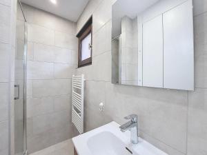 een witte badkamer met een wastafel en een spiegel bij Oree de Morzine 32B in Montriond