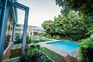 a swimming pool in a yard with two lawn chairs at Bonne Esperance Boutique Guest House in Stellenbosch