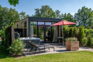 a tiny house with a bench and an umbrella at Wellnesslodge Specht in Dalerveen