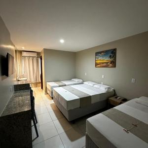 Habitación de hotel con 3 camas y TV en Onix Hotel Aeroporto en Lauro de Freitas