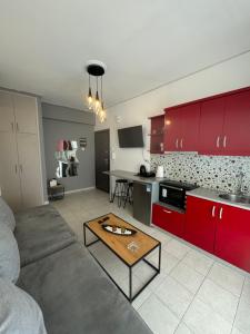 a living room with a couch and a kitchen with red cabinets at Mano’s House Preveza in Preveza