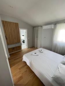 una camera da letto con un grande letto bianco e pavimenti in legno di Lungomare Apartments a Petrovac na Moru