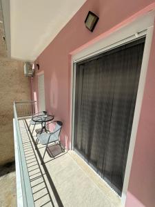 a balcony with two chairs and a table on a pink wall at Mano’s House Preveza in Preveza