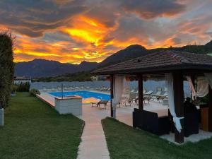 een zonsondergang boven een zwembad met een prieel bij Hotel Merloni in Grandola ed Uniti