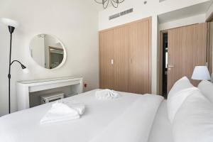 1 dormitorio con 2 camas blancas y espejo en Beautiful 1 BR with Gym, Pool & Kid's Playground, en Dubái