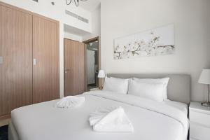 Un dormitorio con una cama grande con sábanas blancas. en Beautiful 1 BR with Gym, Pool & Kid's Playground, en Dubái