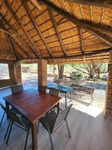 a wooden table and chairs under a wooden roof at Bateleur Lodge, Mabalingwe in Warmbaths +18 photos