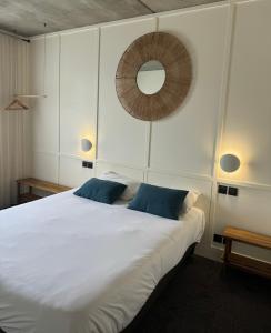 - une chambre avec un grand lit blanc et des oreillers bleus dans l'établissement Théo Hôtel Limoges, The Originals City, à Limoges
