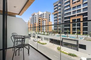 Una silla en un balcón con vista a una ciudad. en Beautiful 1 BR with Gym, Pool & Kid's Playground, en Dubái