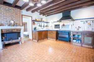 a large kitchen with wooden cabinets and blue appliances at La Maison aux Mille Fleurs in Mosnes +19 photos