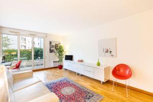 un soggiorno con divano bianco e sedia rossa di GuestReady - Era uma vez em Montparnasse a Parigi
