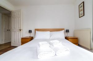 1 dormitorio con 1 cama blanca y 3 toallas en GuestReady - Parkside getaway in Britannia Village, en Londres