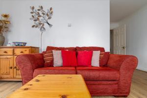 uma sala de estar com um sofá vermelho com almofadas vermelhas e brancas em GuestReady - Parkside getaway in Britannia Village em Londres