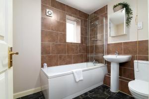 ein Badezimmer mit einer Badewanne, einem Waschbecken und einem WC in der Unterkunft GuestReady - Parkside getaway in Britannia Village in London