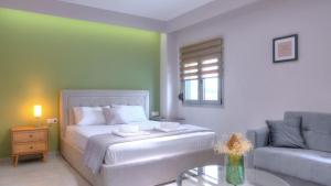 a bedroom with a bed and a couch and a table at Loutsiana Apartments Corfu in Alykes Potamou